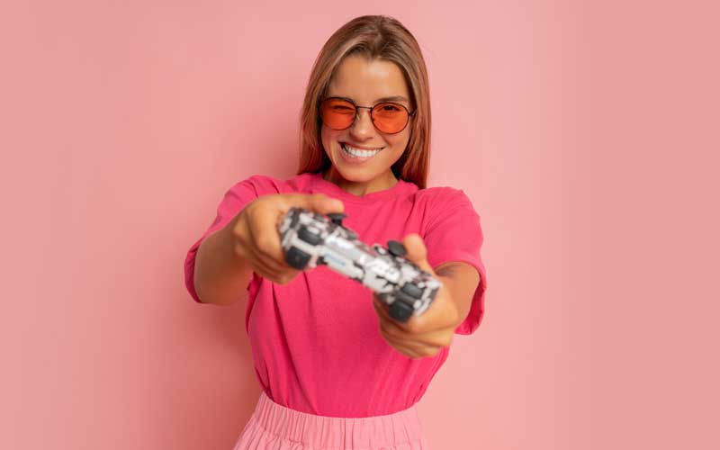 Chica en pared rosa con un mando de consola