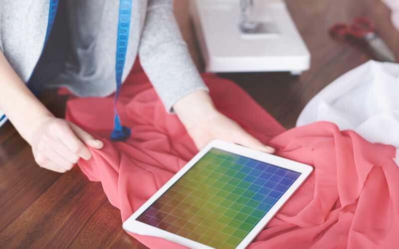 Mesa con telas y una tablet con una paleta de colores