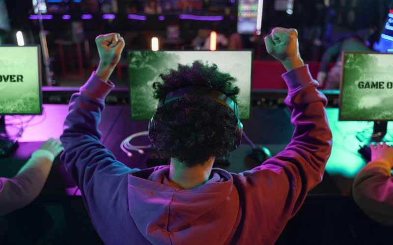 Chico celebrando una partida de un juego en el ordenador