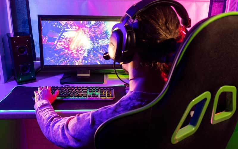 Persona en una habitación sentado frente a un ordenador jugando a un videojuego