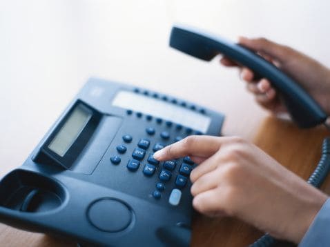 persona cogiendo un teléfono y marcando un número