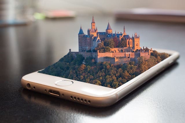teléfono móvil en una mesa y sobresale de la pantalla un castillo en 3d